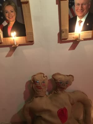 Two effigies beneath candlelit portraits of elected officials, 25 March 2016.