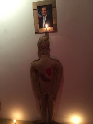 Effigy beneath a candlelit portrait of an elected official, 25 March 2016.