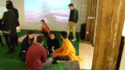 Visitors sitting on the turf by a projection, 11 April 2016.