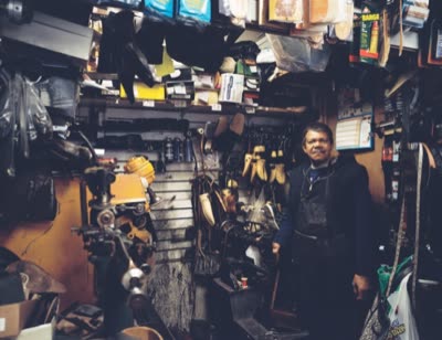 Lindsay Blatt, from Repair & Shine: shoe repairman in a crowded shop, 2008, large-format photograph.