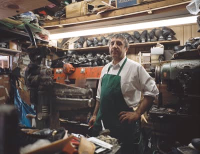 Lindsay Blatt, from Repair & Shine: shoe repairman in a green apron, 2008, large-format photograph.